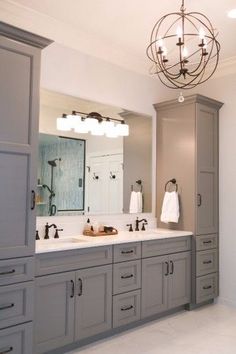 a large bathroom with two sinks and gray cabinets