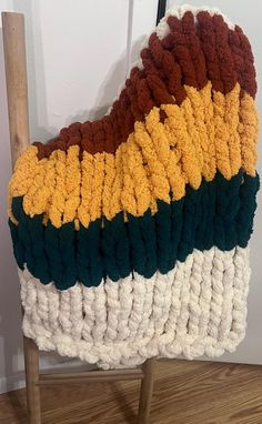 a crocheted blanket sitting on top of a wooden chair next to a wall