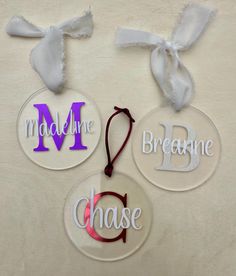 three personalized ornament hanging on a white tablecloth with ribbons and ribbon