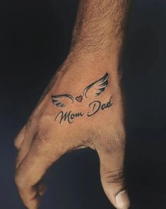 a man's hand with a tattoo on it that says mom dad and an angel wing