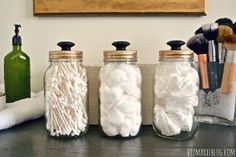 three jars filled with different types of items on top of a wooden table in front of a painting