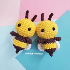 two crocheted yellow and brown bugs sitting next to each other on top of a blue surface