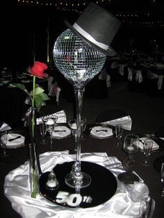 a disco ball centerpiece on top of a table with silverware and wine glasses