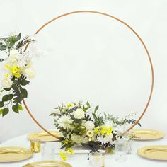 a table topped with plates and flowers on top of a white table cloth covered in gold foil