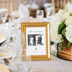 the table is set with white flowers, silverware and framed photos for guests to take pictures