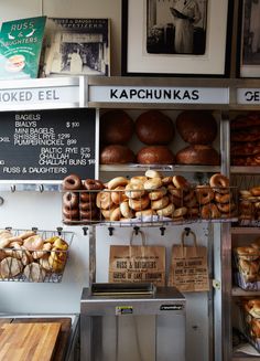 there are many different types of doughnuts on display in the shop window, including bagels and muffins