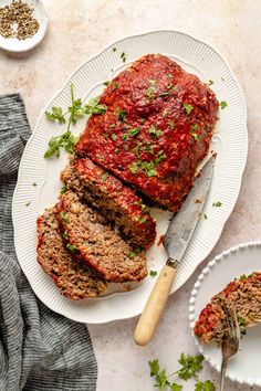 sliced meatloaf on a plate with a knife and parsley next to it