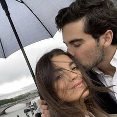 a man and woman kissing under an umbrella