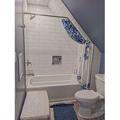 a white toilet sitting next to a bath tub in a bathroom under a slanted ceiling