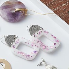 three pairs of earrings sitting on top of a white tray next to a donut