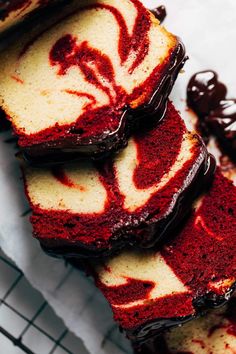 slices of red velvet cake on a cooling rack with chocolate sauce drizzled over them