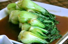 some broccoli sitting on top of a white plate with sauce in the middle