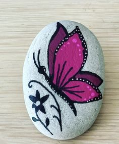 a painted rock with a pink butterfly on it