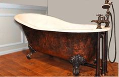 an old fashioned bathtub in a bathroom with wood floors and white walls, along with two faucets