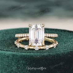 an emerald colored diamond engagement ring set on top of a green velvet cushioned box