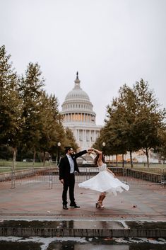 a bride and groom dancing in front of the capital building