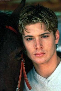 a young man standing next to a horse