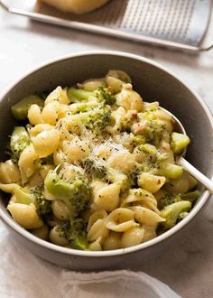 a bowl filled with macaroni and broccoli on top of a table