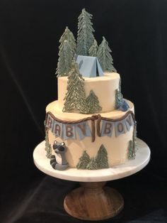 a birthday cake decorated with trees and an origami bear on top is sitting on a pedestal