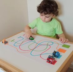 a little boy playing with cars on a table