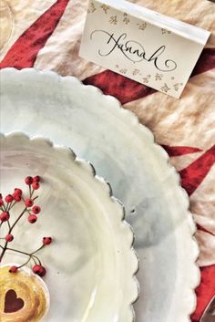 two white plates with red berries on them and a place card in the middle one