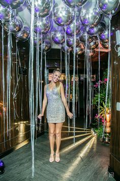 a woman standing in front of balloons and streamers