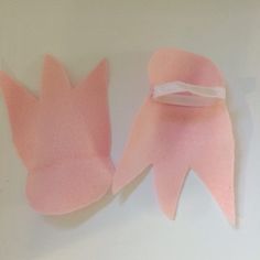 two pieces of pink paper with white ribbon on them sitting next to each other in front of a white wall