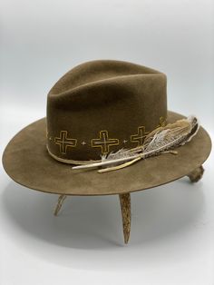 Western weight 100x beaver felt in color whiskey Teardrop crown Flat brim, 3" wide Elk leather strap and feather detail Hand-stitched crosses all around the crown All felt hats are made to order, please allow 8 weeks for delivery Felt Hats, Boho Hat, Felt Hat, 8 Weeks, Hat Sizes, The Crown, Hat Designs, Hand Stitched