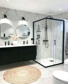 a modern bathroom with black and white fixtures, marble counter tops, and round mirrors