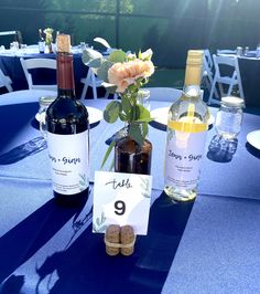 two bottles of wine are sitting on a table with place cards and corks in front of them