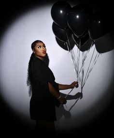 a woman holding onto some black balloons