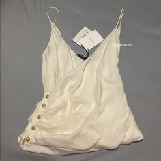 Nwt Balmain Paris. Cross Front Silk Camisole. Fr Size 36 (Us 4). 100% Silk Camisole Pleated, V-Neck Embossed Gold-Tone Buttons On Side, Low Cut In Back Authentic - Poshmark Will Authenticate Items Over $500 White Tank Top For Spring Evening, White Sleeveless Tank Top For Evening, White Sleeveless Camisole For Evening, Elegant White Cami Tank Top, White Elegant Camisole Tank Top, Elegant White Camisole Tank Top, White Camisole Tops For Evening, White Evening Camisole For Spring, Cream Sleeveless Evening Top