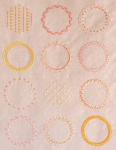 a bunch of different types of bracelets on top of a white cloth with orange and yellow thread