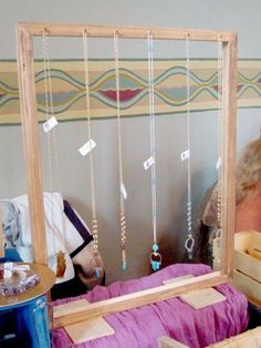 a woman sitting in front of a mirror with necklaces hanging from it