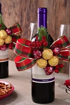 two wine bottles with christmas decorations on them and some pretzels in the middle