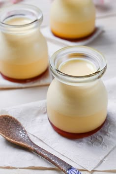 two jars filled with pudding sitting on top of a table next to a wooden spoon