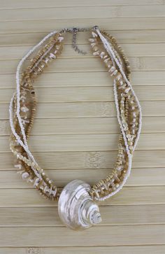 White Multi-strand Pearl Beaded Necklaces, Pearl White Shell Necklace, Pearl White Shell Necklace For Beach, White Abalone Shell Necklace For Beach, Cream Shell-shaped Shell Jewelry, White Abalone Shell Beach-style Necklace, Bohemian White Pearl Shell Necklace, Beaded Pearl White Shell Necklace, White Pearl Bohemian Shell Necklace