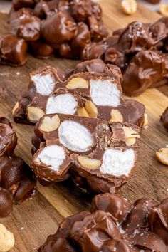 chocolate and marshmallows are arranged on a wooden cutting board with other treats