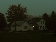 a white house sitting in the middle of a forest at night