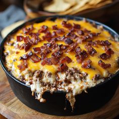 a cheesy dish with bacon and cheese in a skillet on a cutting board