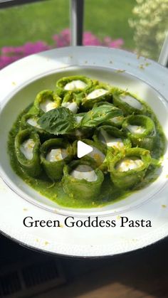 a white plate topped with green vegetables covered in pesto and ice cream on top of a window sill