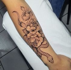 a snake and flowers tattoo on the arm