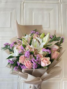 a bouquet of flowers sitting on top of a white table next to a wooden wall