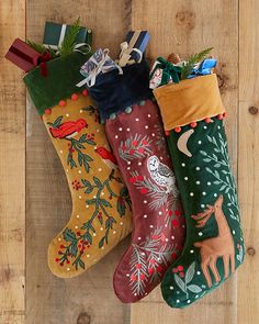 three christmas stockings hanging on a wooden floor with presents in the bottom one is tied up