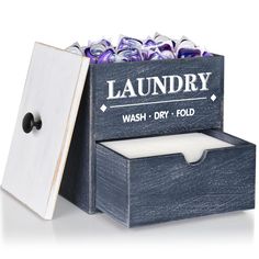 a wooden box filled with lots of purple and white flowers next to a sign that says laundry wash dry fold