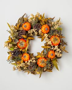 a wreath with pumpkins, berries and pine cones