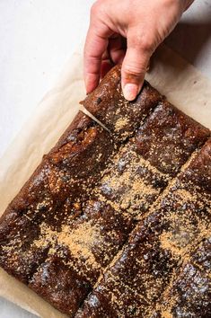 a person cutting up some brownies on top of a piece of waxed paper