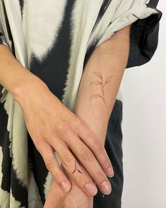 a woman's hand with a small tattoo on her left wrist and the other arm