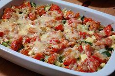 a casserole dish with tomatoes, zucchini and cheese