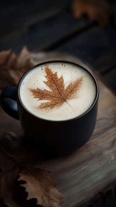 a cup of cappuccino with a leaf drawn on the foam in it